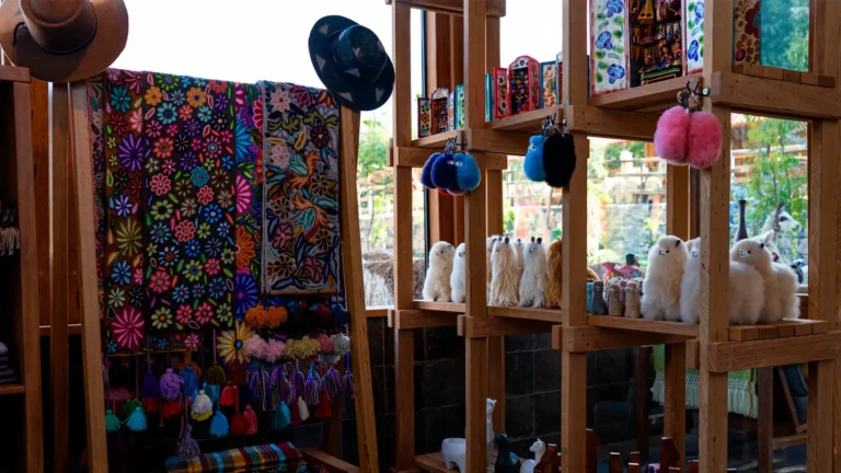 Textiles andinos bordados a mano, sombreros y artesanías locales expuestas en estantes de madera fina dentro de la boutique exclusiva del hotel.
